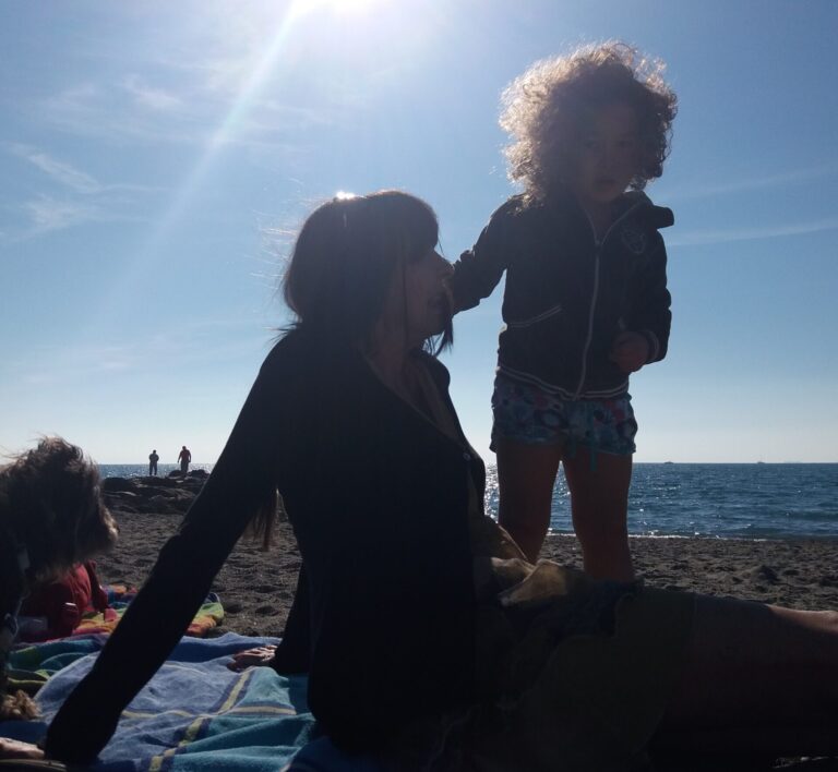 Blog di viaggi rigenerativi – Stay Hamlet – Serenella Messina su una spiaggia ligure con la piccola Aurora e il bassotto Mario
